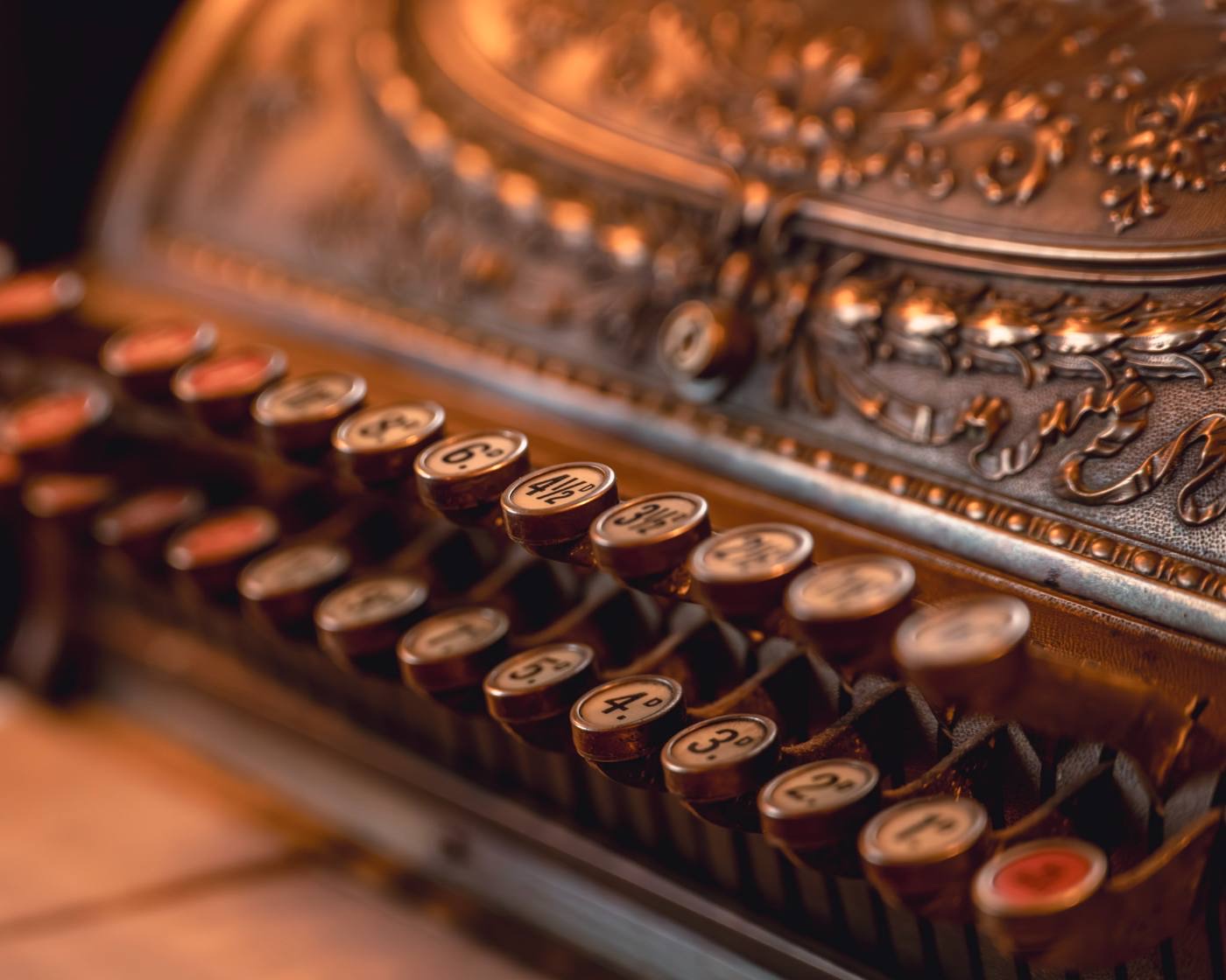 Close detail of an ornate brass antique cash register with embossed casework