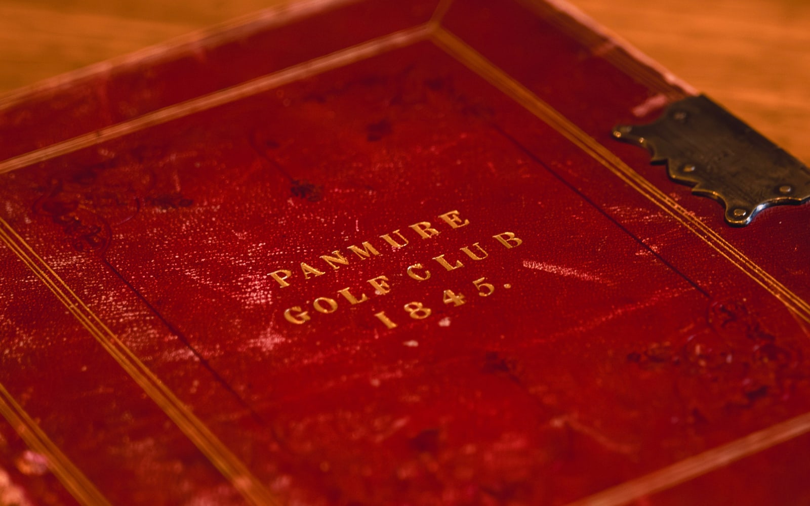 The red leather-bound club minute book on a polished table, gilt-embossed Panmure Golf Club 1845, with its brass clasp