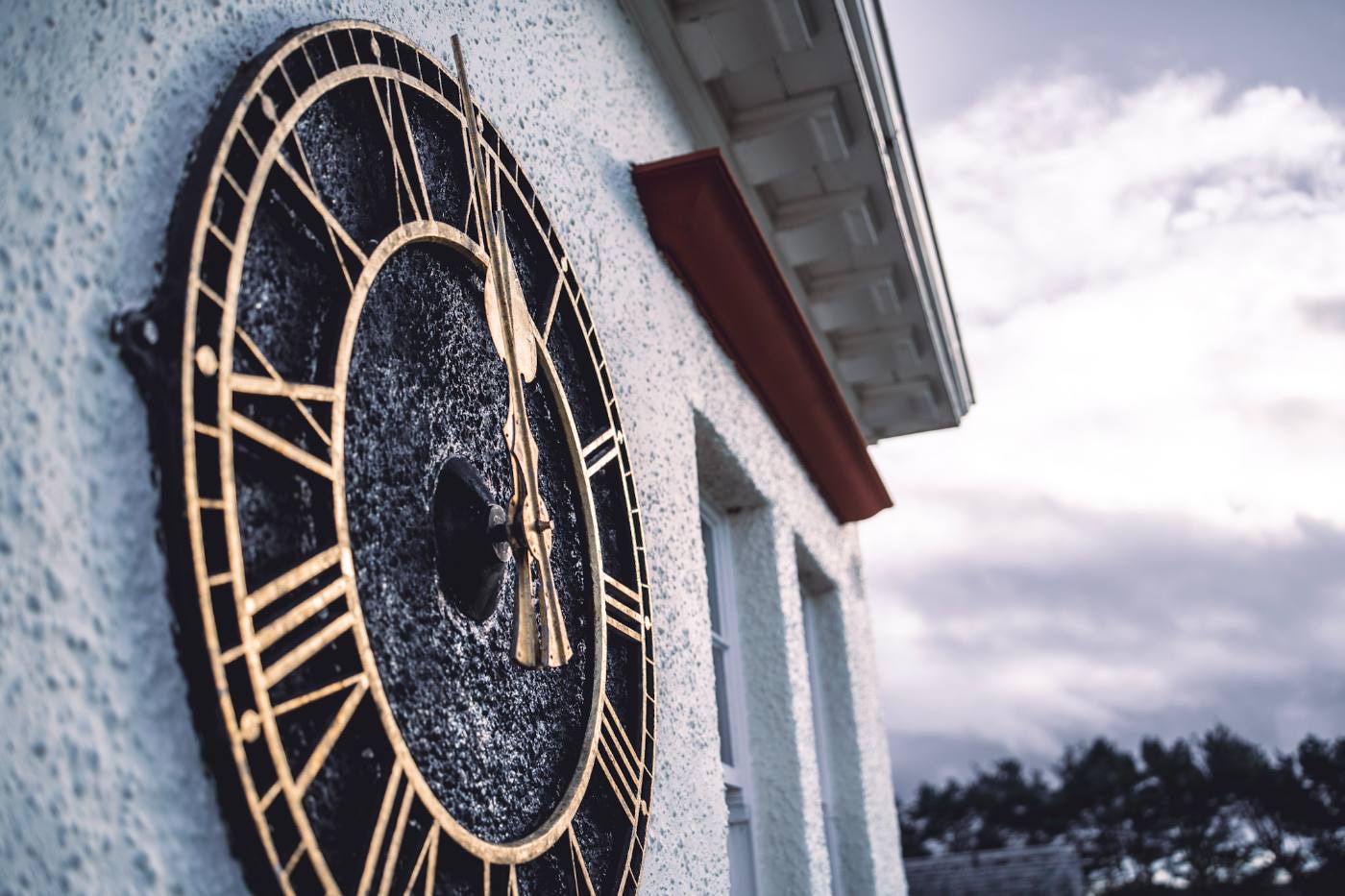 Detail of the clubhouse clock face set into the white harled gable, shot from below