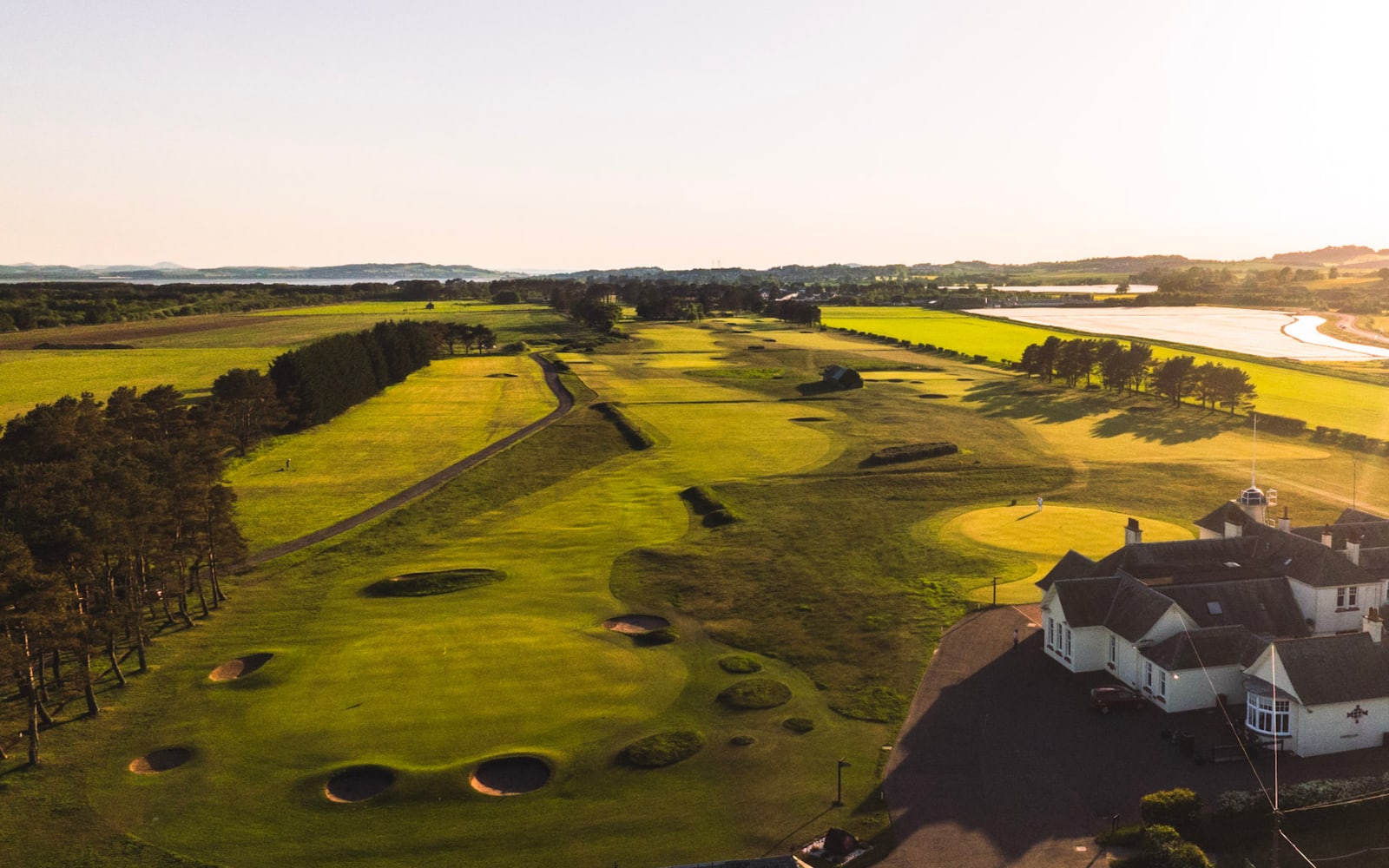 The Calcutta, hole 18 at Panmure, from the air in evening light: the fairway and its bunkering running home to the green beside the clubhouse