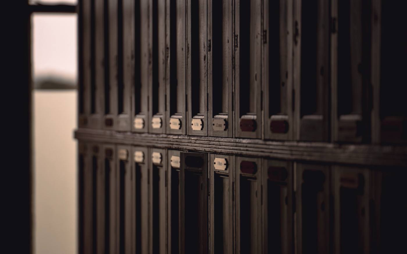 The locker room: banks of tall wooden lockers with brass fittings receding down the room