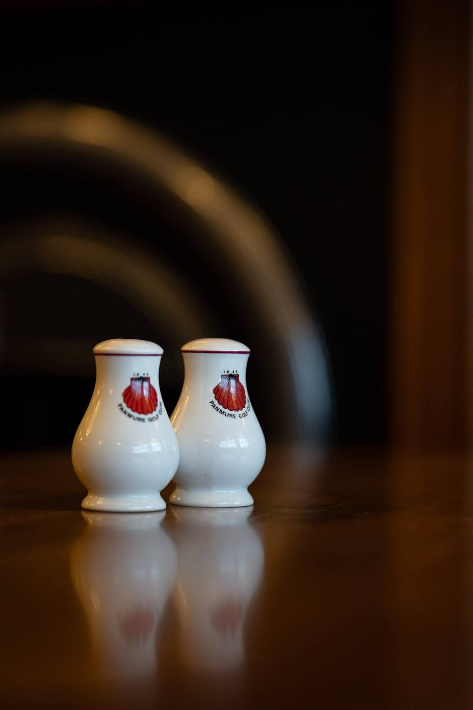 A pair of white china salt and pepper cruets carrying the red scallop-shell crest