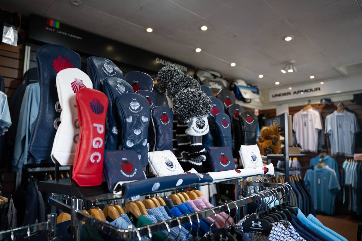 The pro shop interior, racks of clothing and headcovers on a stand